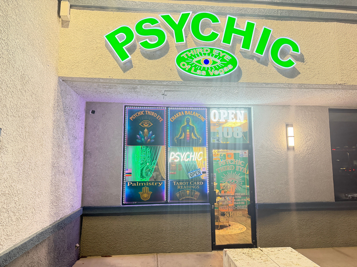 Psychic Third Eye store front with neon Open sign, Chakra Balancing, Palmistry, and Tarot Card Reading signs.